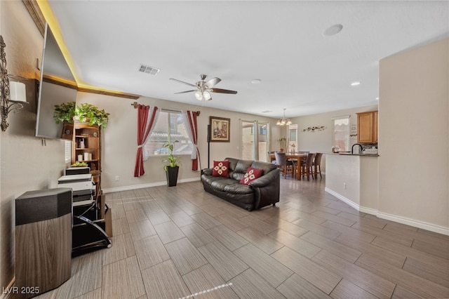 living area featuring a ceiling fan, baseboards, recessed lighting, wood finish floors, and a chandelier