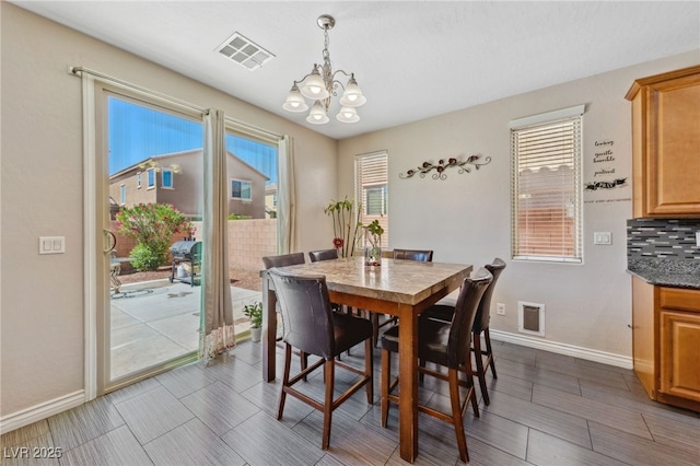 dining space featuring a chandelier, baseboards, and wood finish floors