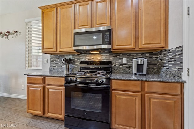 kitchen featuring black gas stove, stainless steel microwave, decorative backsplash, and baseboards