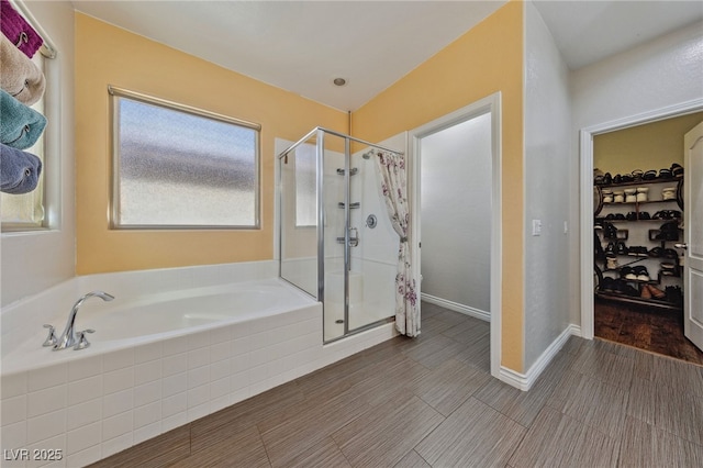 bathroom with a stall shower, a walk in closet, and a garden tub