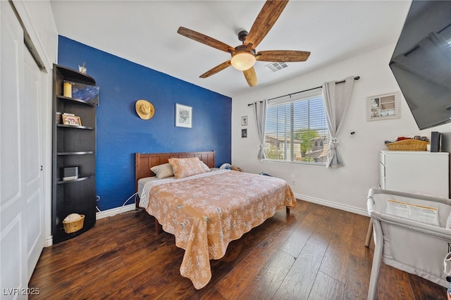 bedroom with wood finished floors, baseboards, a ceiling fan, and an accent wall