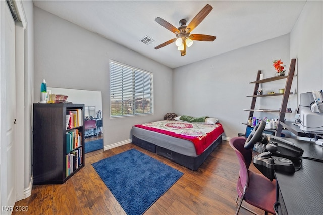 bedroom featuring an office area, wood finished floors, baseboards, and ceiling fan
