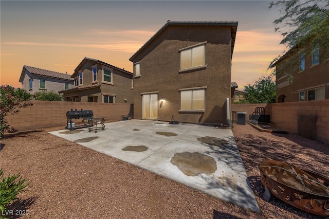 6409 Dundock Ave, Las Vegas, NV 89122 - back of property at dusk featuring a fire pit, a patio, and a fenced backyard