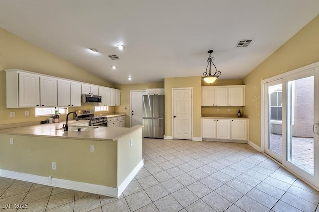 kitchen featuring appliances with stainless steel finishes, vaulted ceiling, a peninsula, a sink, and light countertops