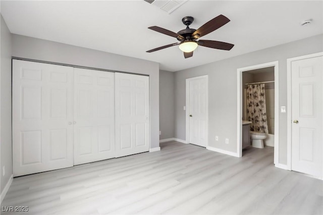 unfurnished bedroom with light wood-type flooring, baseboards, connected bathroom, a closet, and ceiling fan