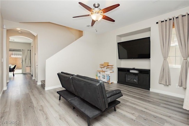 8717 Early Horizon Dr, Las Vegas, NV 89178 - living room with light wood-type flooring, arched walkways, ceiling fan, and baseboards