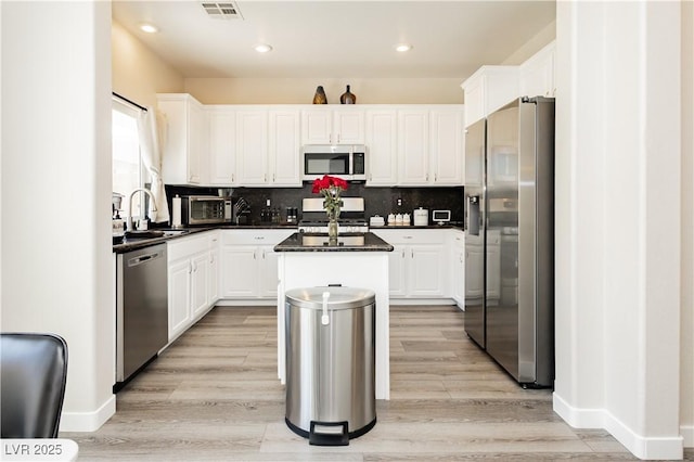 8717 Early Horizon Dr, Las Vegas, NV 89178 - kitchen with appliances with stainless steel finishes, a sink, dark countertops, a center island, and white cabinetry