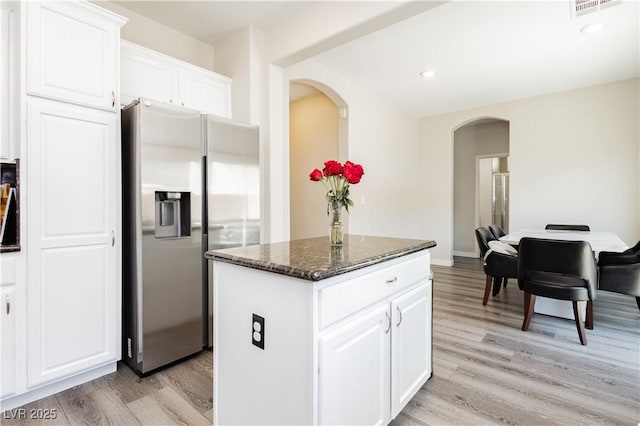 8717 Early Horizon Dr, Las Vegas, NV 89178 - kitchen with stainless steel refrigerator with ice dispenser, arched walkways, light wood-style flooring, a center island, and dark stone countertops