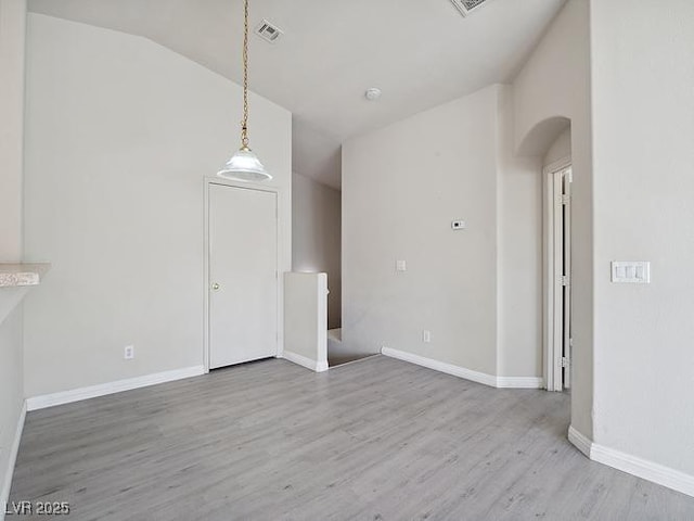 4830 Double Down Dr Unit 102, Las Vegas, NV 89122 - unfurnished living room featuring arched walkways, wood finished floors, vaulted ceiling, and baseboards
