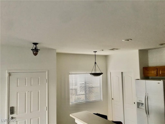 4830 Double Down Dr Unit 102, Las Vegas, NV 89122 - kitchen featuring white refrigerator with ice dispenser, pendant lighting, and brown cabinetry