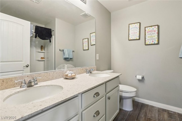 334 E Neal Ave, Las Vegas, NV 89183 - bathroom featuring toilet, wood finished floors, double vanity, baseboards, and a shower