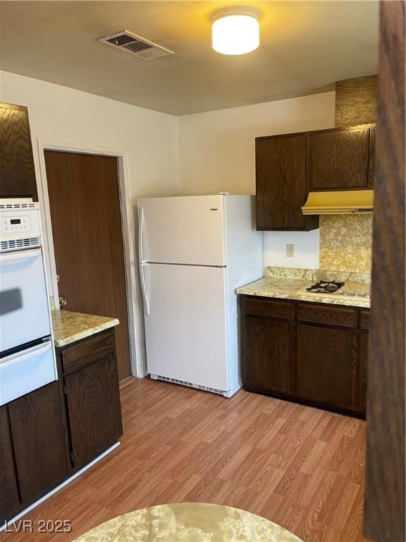4564 Dennis Way, Las Vegas, NV 89121 - kitchen featuring white appliances, a warming drawer, light wood-style floors, and dark brown cabinetry