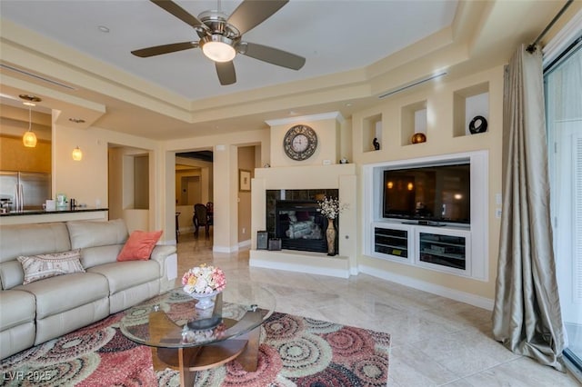 9201 Tesoras Dr Unit 302, Las Vegas, NV 89144 - tiled living room featuring a raised ceiling, a glass covered fireplace, ceiling fan, and baseboards