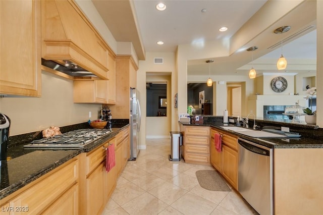 9201 Tesoras Dr Unit 302, Las Vegas, NV 89144 - kitchen with stainless steel appliances, light tile patterned floors, light brown cabinets, dark stone countertops, and pendant lighting