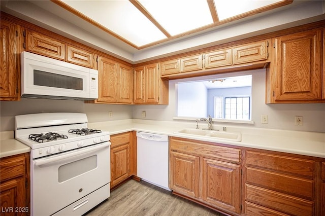 kitchen with white appliances, a sink, and light countertops
