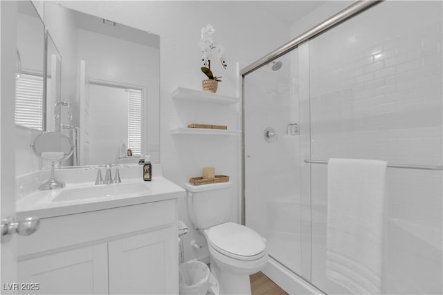 bathroom featuring a stall shower, toilet, vanity, and wood finished floors