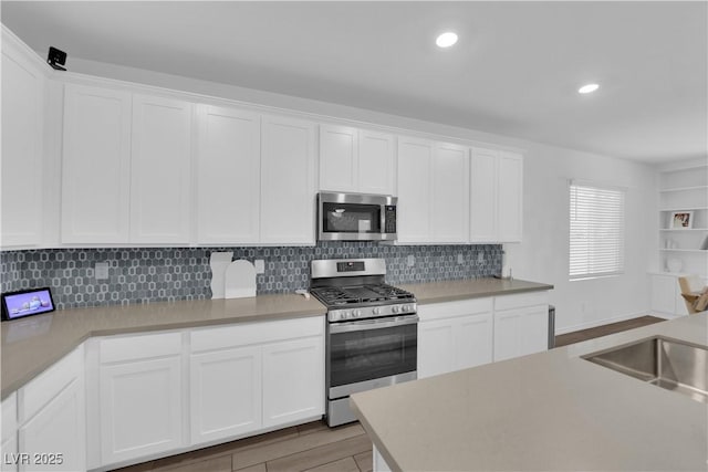 kitchen with stainless steel appliances, white cabinetry, light wood finished floors, backsplash, and recessed lighting