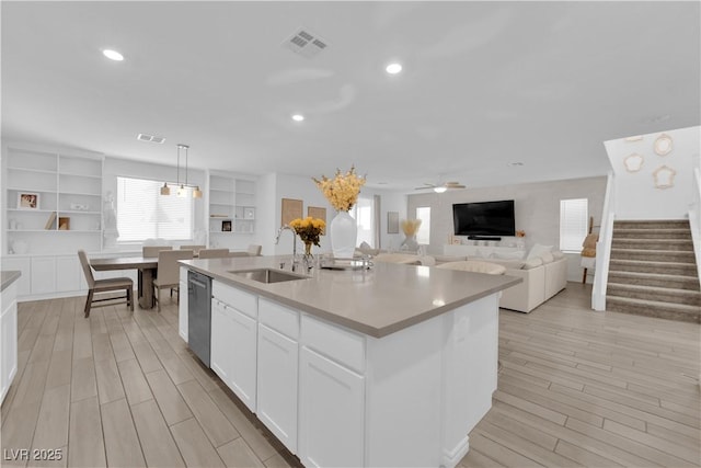 kitchen featuring a sink, dishwasher, light wood finished floors, white cabinets, and ceiling fan