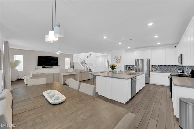 kitchen with appliances with stainless steel finishes, a sink, open floor plan, tasteful backsplash, and recessed lighting