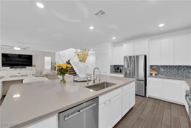 kitchen with appliances with stainless steel finishes, a sink, decorative backsplash, a ceiling fan, and white cabinets