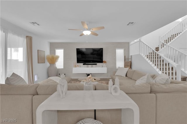 living area featuring stairs and ceiling fan