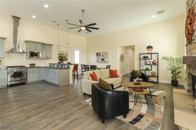 1409 Denver St, Boulder City, NV 89005 - living room featuring a ceiling fan, wood finished floors, a towering ceiling, a fireplace, and baseboards