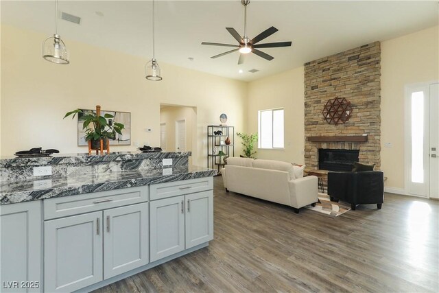 1409 Denver St, Boulder City, NV 89005 - kitchen featuring a ceiling fan, wood finished floors, hanging light fixtures, dark stone counters, and a high ceiling