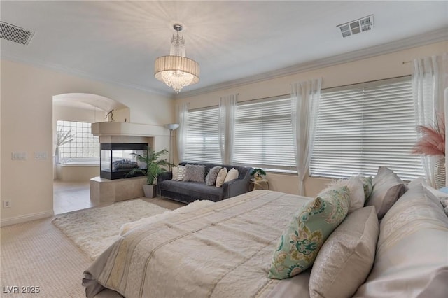 7112 Rancho De Taos Ct, Las Vegas, NV 89130 - carpeted bedroom featuring arched walkways, crown molding, baseboards, a chandelier, and a multi sided fireplace