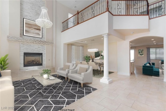 7112 Rancho De Taos Ct, Las Vegas, NV 89130 - tiled living area with a towering ceiling, arched walkways, a tile fireplace, decorative columns, and baseboards