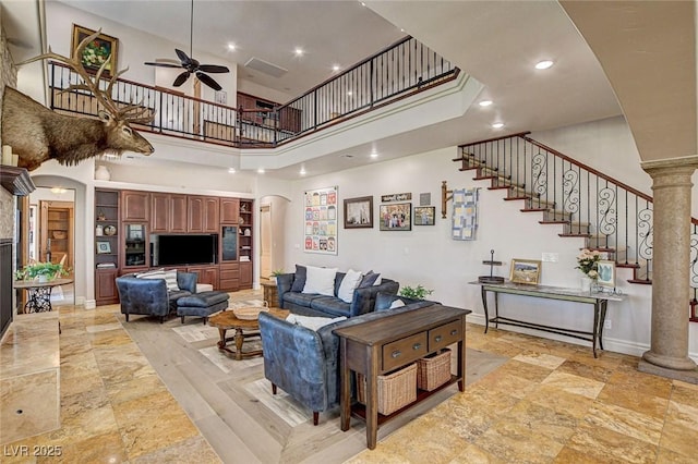 1182 Thomas Bay Cir, Logandale, NV 89021 - living area with a high ceiling, a ceiling fan, arched walkways, stairway, and stone tile floors