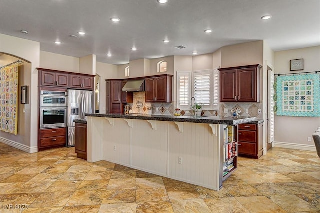 1182 Thomas Bay Cir, Logandale, NV 89021 - kitchen with stainless steel appliances, a breakfast bar area, ventilation hood, baseboards, and stone tile floors