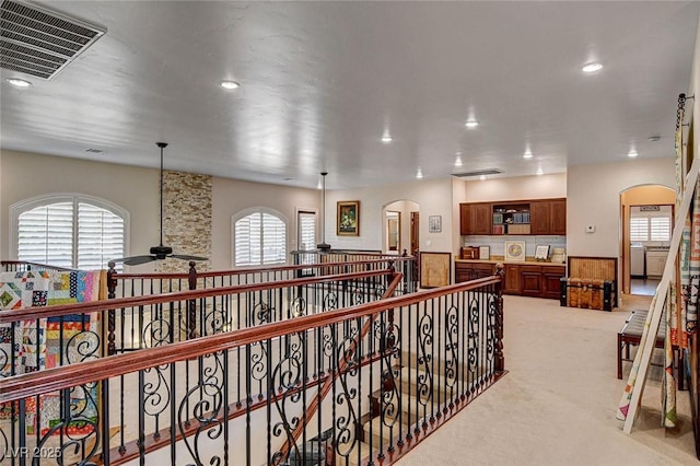 1182 Thomas Bay Cir, Logandale, NV 89021 - hall with arched walkways, light colored carpet, recessed lighting, and an upstairs landing
