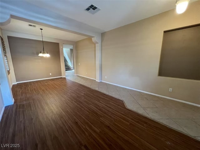 tiled empty room with stairway, baseboards, and a chandelier