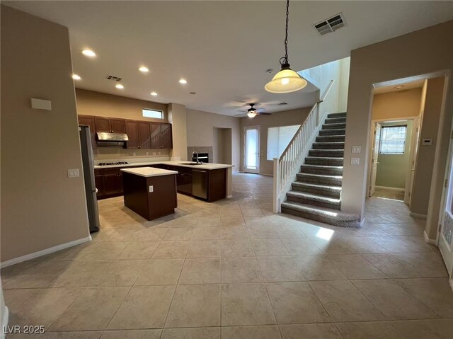 kitchen featuring a kitchen island, light countertops, stainless steel appliances, ceiling fan, and a sink