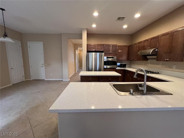 kitchen with appliances with stainless steel finishes, a sink, under cabinet range hood, dark brown cabinets, and light tile patterned floors