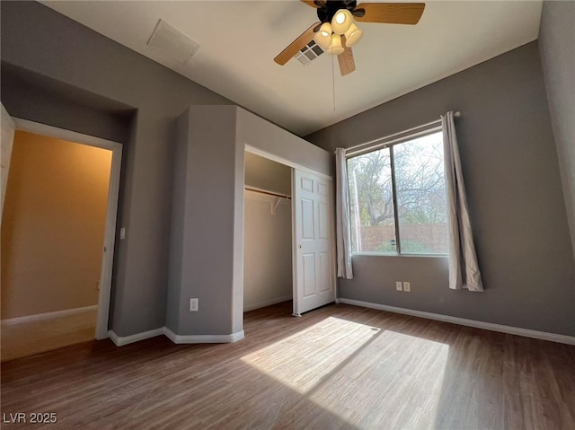 unfurnished bedroom with wood finished floors, baseboards, a closet, and a ceiling fan