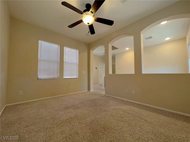 carpeted empty room featuring ceiling fan, arched walkways, baseboards, and recessed lighting