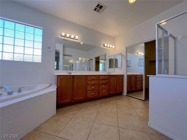 bathroom featuring a stall shower, tile patterned floors, double vanity, and a garden tub