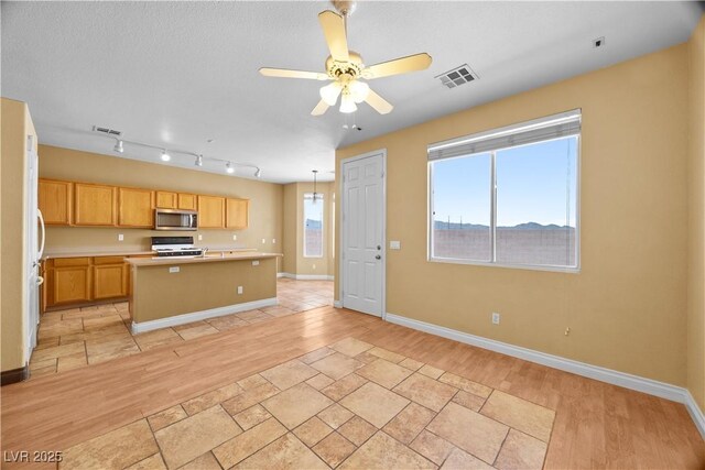 6088 Gulf Island Ave, Las Vegas, NV 89156 - kitchen featuring stainless steel microwave, range, light countertops, light wood-style floors, and a kitchen island