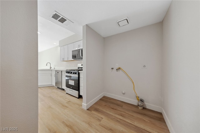 2834 Crystal Lantern Dr, Henderson, NV 89074 - kitchen with appliances with stainless steel finishes, light wood finished floors, and white cabinetry