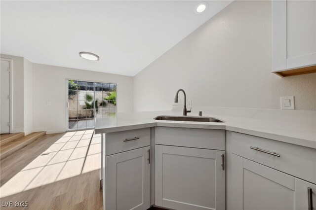 2834 Crystal Lantern Dr, Henderson, NV 89074 - kitchen featuring a sink, light countertops, light wood finished floors, a peninsula, and lofted ceiling
