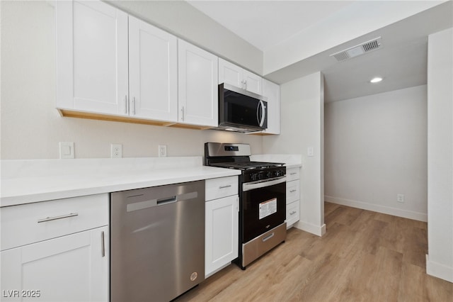 2834 Crystal Lantern Dr, Henderson, NV 89074 - kitchen with stainless steel appliances, white cabinets, light wood finished floors, light countertops, and baseboards