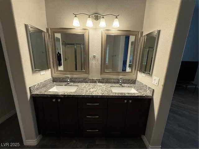 5318 Rio Eldorado Ct, North Las Vegas, NV 89031 - bathroom featuring double vanity, an enclosed shower, baseboards, and a textured wall