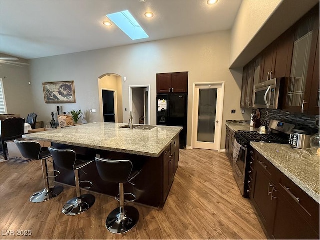 5318 Rio Eldorado Ct, North Las Vegas, NV 89031 - kitchen featuring stainless steel appliances, a sink, arched walkways, a kitchen breakfast bar, and light wood-style flooring