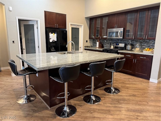 5318 Rio Eldorado Ct, North Las Vegas, NV 89031 - kitchen with appliances with stainless steel finishes, a sink, a kitchen bar, light wood-type flooring, and tasteful backsplash
