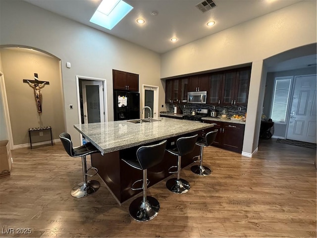 5318 Rio Eldorado Ct, North Las Vegas, NV 89031 - kitchen with appliances with stainless steel finishes, a sink, arched walkways, a skylight, and a breakfast bar area