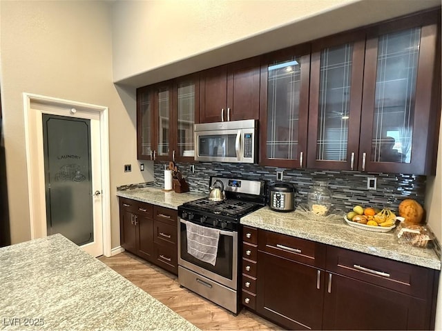 5318 Rio Eldorado Ct, North Las Vegas, NV 89031 - kitchen featuring stainless steel appliances, backsplash, light wood-type flooring, and glass insert cabinets