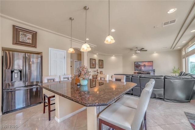 6453 Mount Eden Ave, Las Vegas, NV 89139 - kitchen with stainless steel fridge, a breakfast bar area, dark stone counters, a kitchen island, and ceiling fan