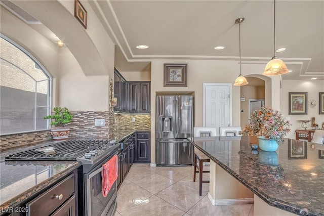 6453 Mount Eden Ave, Las Vegas, NV 89139 - kitchen with appliances with stainless steel finishes, a kitchen breakfast bar, backsplash, and dark stone countertops