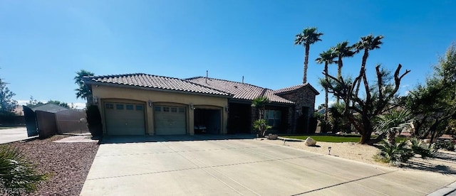 mediterranean / spanish home featuring an attached garage, concrete driveway, a tiled roof, and stucco siding